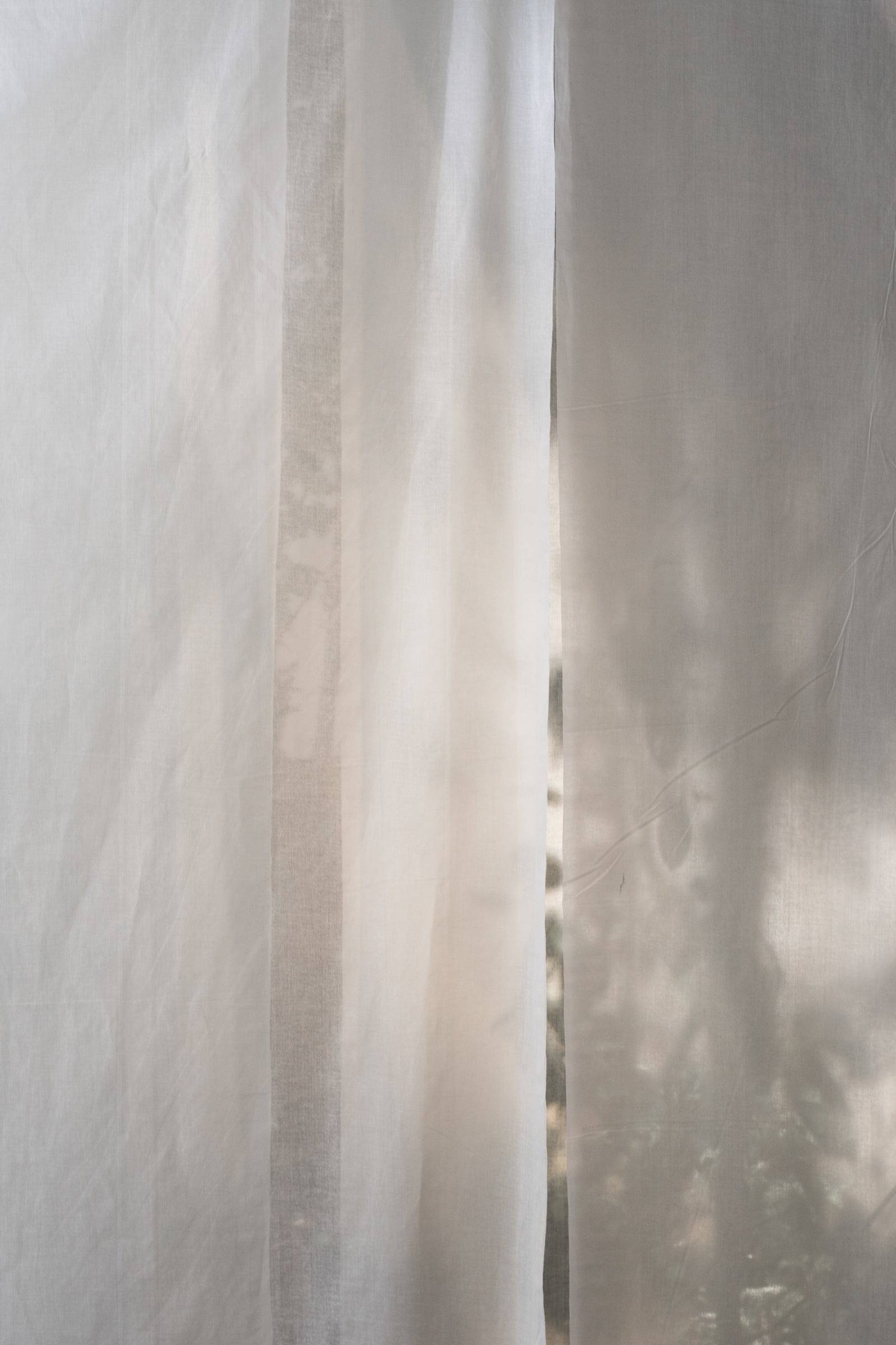 Light linen curtain gently blowing in the breeze—evoking serenity, softness, and the spaciousness of intentional living.