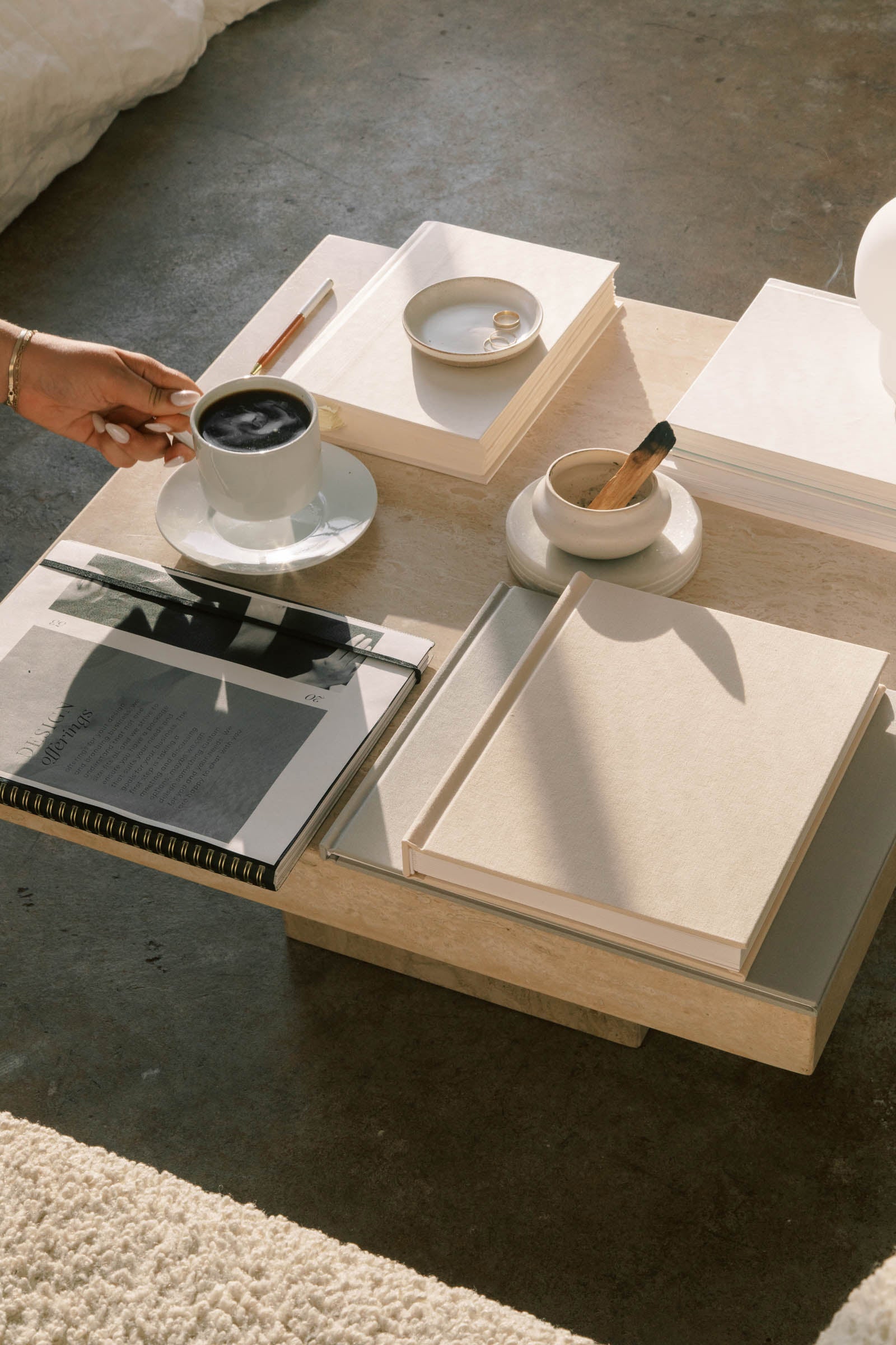 A ceramic cup of coffee and smoldering sage rest on a textured coffee table—symbolizing calm, clarity, and sacred daily rituals.